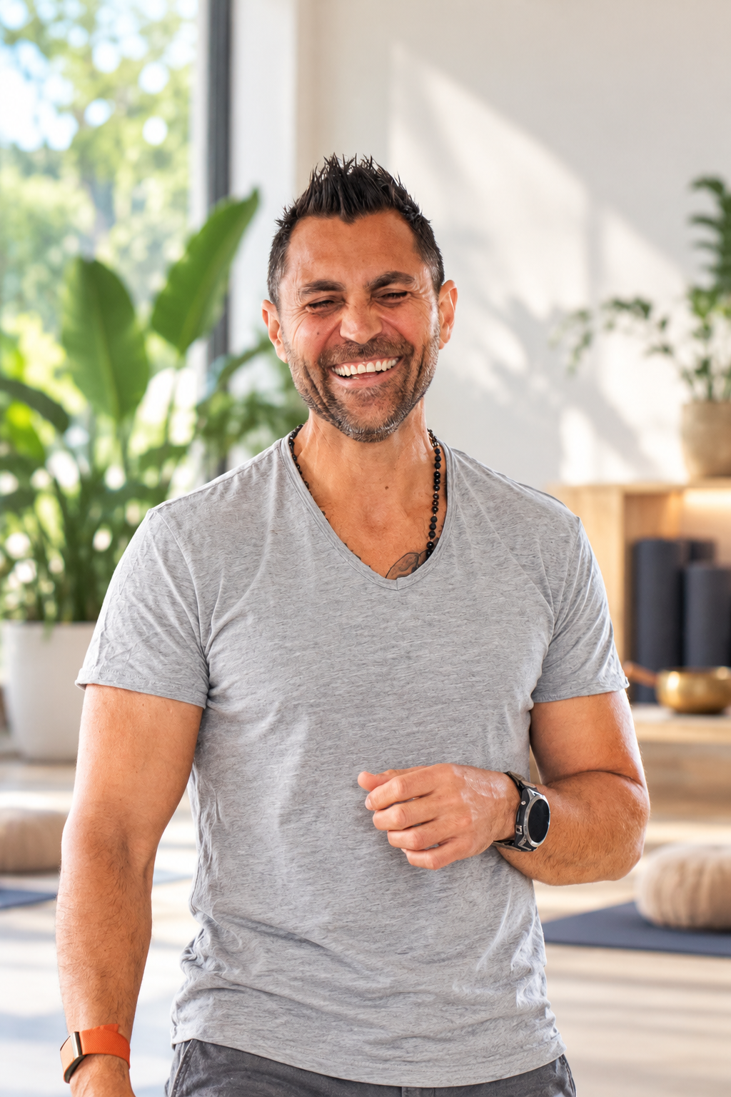 Dino Biordi laughing in a sunlit studio, wearing a grey t-shirt.