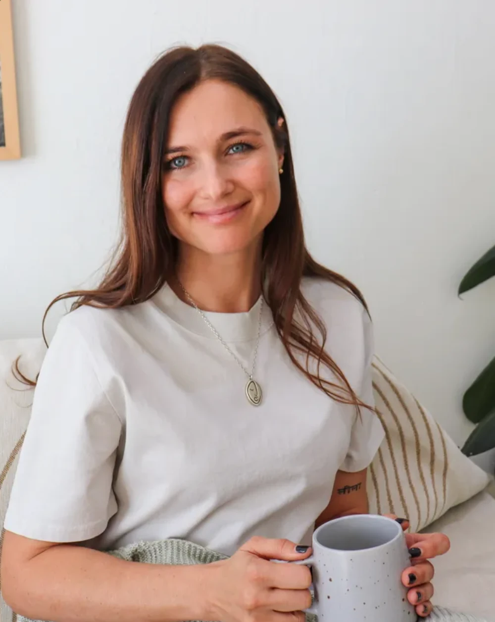 Natalia Paklina, meditation teacher at Prema Meditation, smiling and holding a mug of tea.
