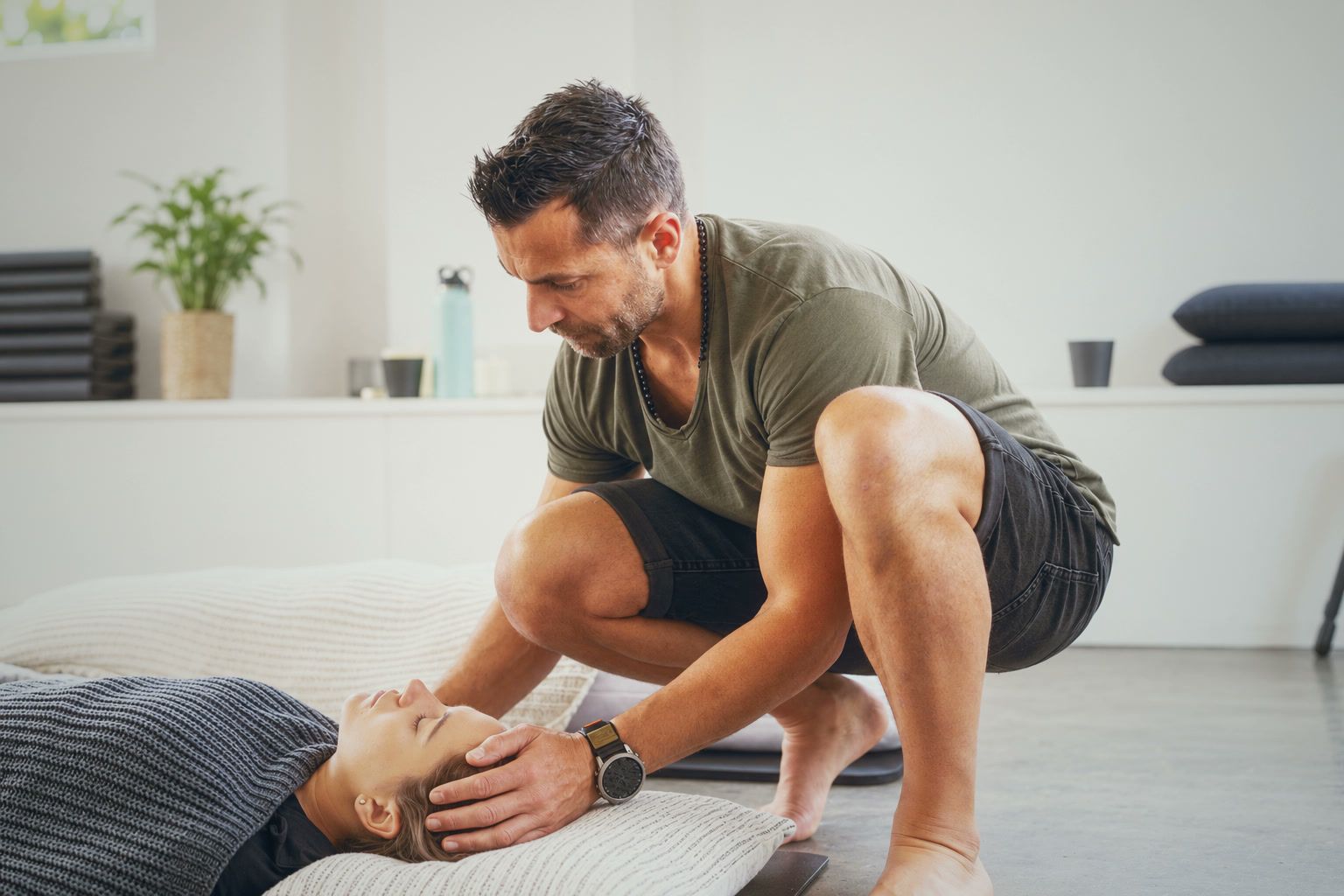 Dino crouching beside a woman lying on a mat, his hand resting lightly on her head.